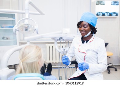 young black girl doctor dentist treats white girl's teeth. - Shutterstock ID 1043112919