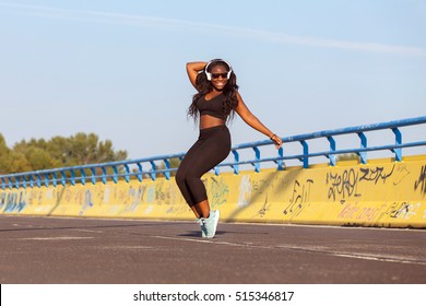 Young black girl with earphone dancing on the street