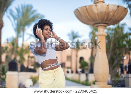 Young black girl listening to the music with headphones. Lifestyle concept