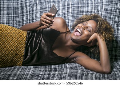 Young Black Girl Talking On The Phone Lying On The Sofa