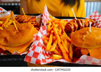 Young Black Haired Girl Holding A Tray Of Junk Food. Brunette Holding Fries And Cheeseburger. Delicious Potatoes And Burgers On A Tray. Spicy Chicken Tender. Waitress Serving Fast Food. 