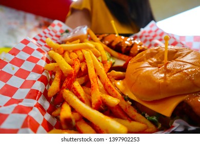 Young Black Haired Girl Holding A Tray Of Junk Food. Brunette Holding Fries And Cheeseburger. Delicious Potatoes And Burgers On A Tray. Spicy Chicken Tender. Waitress Serving Fast Food. 