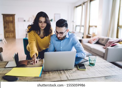 Young Black Haired Woman Coach In Sweater And Pencil In Hand Tutoring Man In Stylish Glasses With Digital Tablet And Laptop At Home 