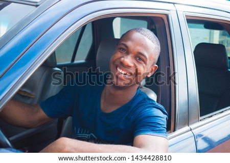 young black handsome cab driver smiling inside his blue car