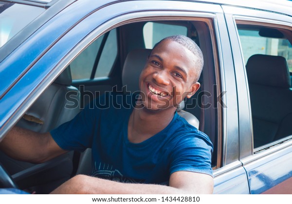 young black handsome cab driver smiling inside his\
blue car