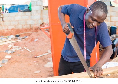 Young Black Happy Carpenter Sawing A Wood In His Workshop