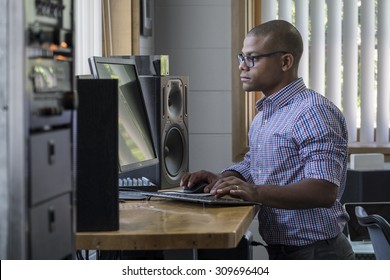 Young Black Male Standing At His Computer Desk In An Office