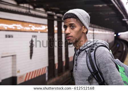A young, black male waits for a New York City subway train. Shot during the autumn of 2016.