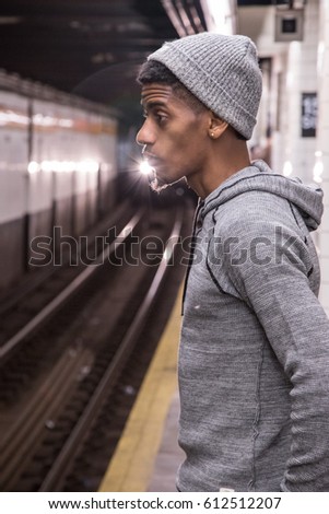 A young, black male waits for a New York City subway train. Shot during the autumn of 2016.