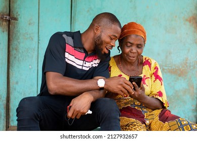 young black man assisting an elderly woman using her phone