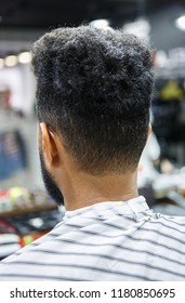 Young Black Man In Barber Shop Covered With Blanket Waiting For Barber Hairdresser To Trim His Neck And Make Pretty Haircut.Male Beauty Treatment Process In Close Up