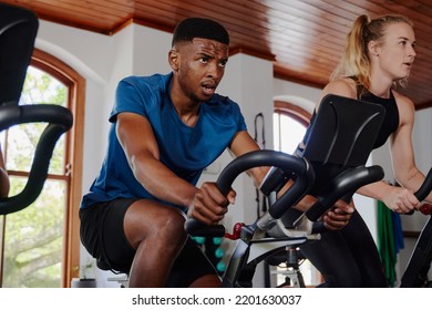 Young Black Man And Caucasian Woman Doing Cardio Workout On Exercise Bike At The Gym