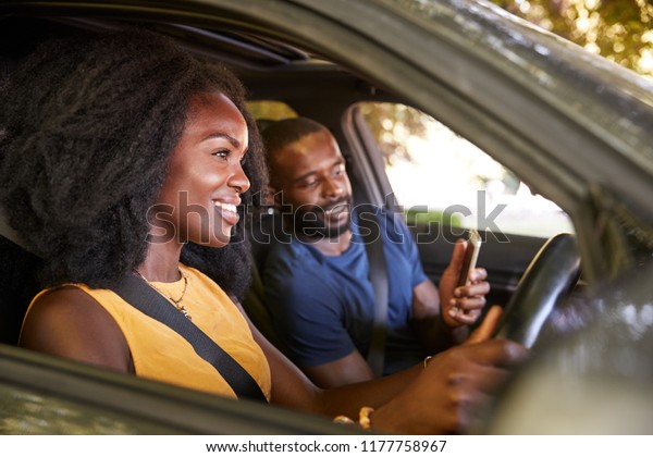A\
young black man checks smartphone during a road\
trip