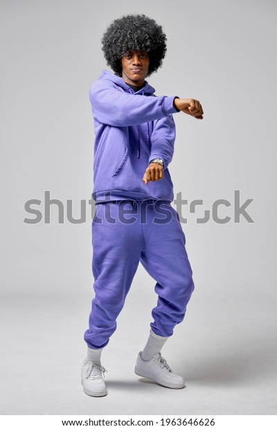 Young black man dancing in blue set of\
tracksuit isolated on gray\
background