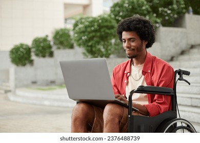 Young Black man with disability working as freelancer, he is answering e-mails on laptop - Powered by Shutterstock