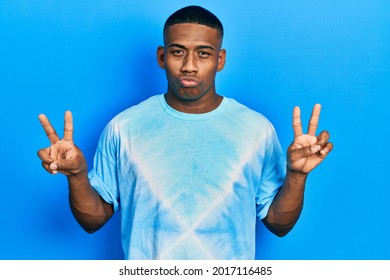 Young Black Man Doing Victory Sign And Peace Gesture Looking At The Camera Blowing A Kiss Being Lovely And Sexy. Love Expression. 