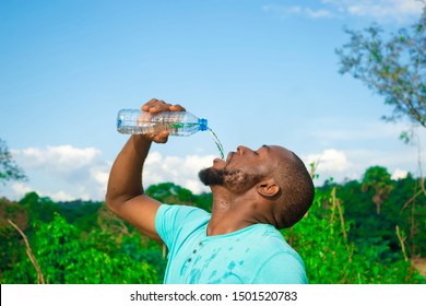 Young Black Man Drinking Water From A Bottle After A Stressful Day In The Farm