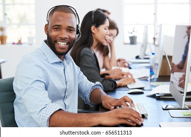 Young Black Man With Headset On Smiling To Camera In Office