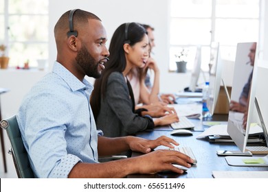 Young Black Man With Headset Working At Computer In Office