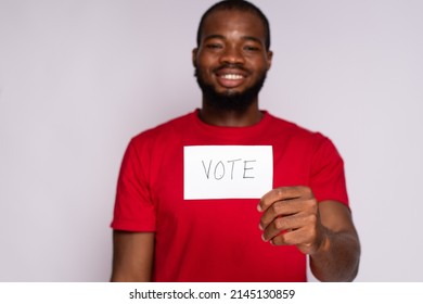 Young Black Man Holding A Card That Says Vote