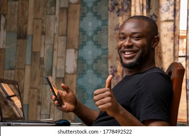 young black man holding his mobile phone smiling and giving the thumbs up - Shutterstock ID 1778492522
