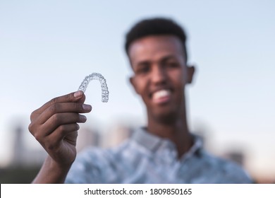 Young Black Man Is Holding An Invisalign Brace And He Has Confident Smiling