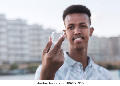 Young Black Man Is Holding An Invisalign Brace And He Has Confident Smiling