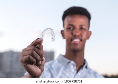 Young Black Man Is Holding An Invisalign Brace And He Has Confident Smiling