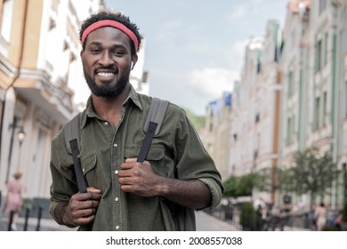 A Young Black Man Laughs While Walking The Streets Of The Bridge With A Backpack