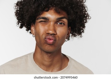 Young black man making kiss lips and winking at camera isolated over white background