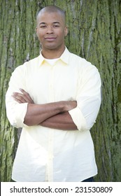 A Young Black Man Outdoors With A Green Background On A Sunny Day.