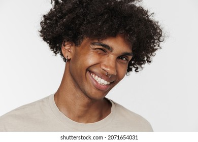 Young black man with piercing smiling and winking at camera isolated over white background