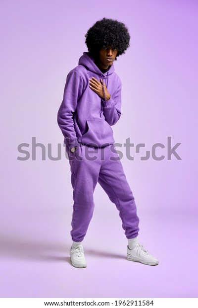 Young black man in purple tracksuit dancing in white\
sneakers 