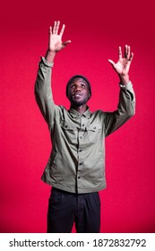 Young Black Man Reaching Up With Arms Raised. Isolated Background. Medium Shot. 