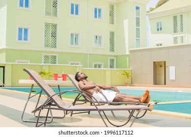 Young Black Man Relaxing By The Pool Side On A Bright Sunny Day