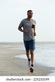 Young Black Man Running On Beach To Keep Fit