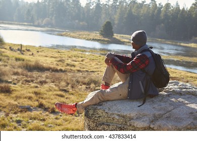 Young Black Man Sitting Alone On A Rock In Countryside