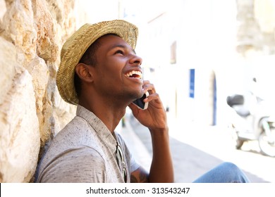 Young Black Man Smiling And Talking On Mobile Phone Outside