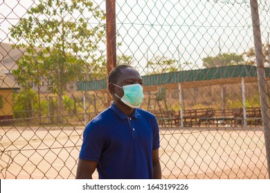 Young Black Man Standing Alone Outside Wearing A Medical Face Mask