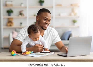 Young Black Man Study With Laptop At Home And Taking Care About Baby, African American Father Using PC Computer For Online Education While Babysitting His Adorable Infant Child, Copy Space