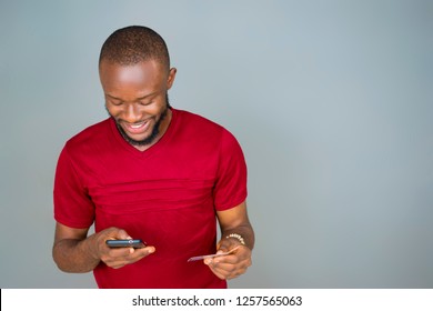 Young Black Man Trying To Make A Payment Online With His Mobile Phone And Holding His Credit Card 