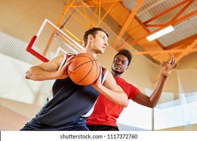 Young Black Man Trying To Stop Contender From Shooting Goal While Playing Basketball Together In Gym.