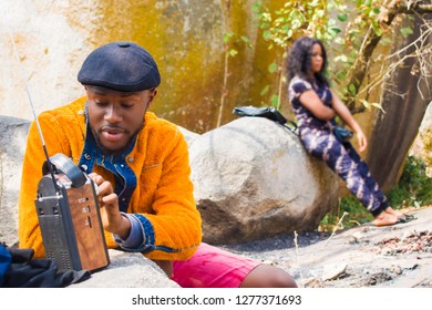 Young Black Man Tuning His Radio In A Rocky Environment