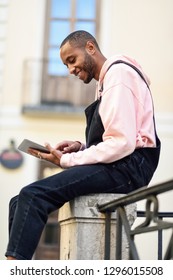 Young black man using digital tablet in urban background. Lifestyle and technology concepts.