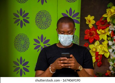 Young black man using a face mask to prevent himself from virus and pressing his phone