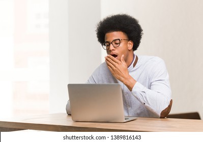 Young black man using his laptop tired and very sleepy
