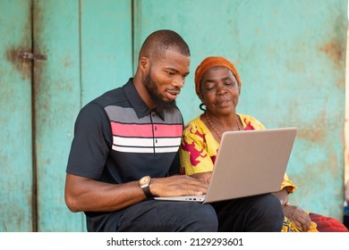 Young Black Man Using A Laptop With An Old Woman