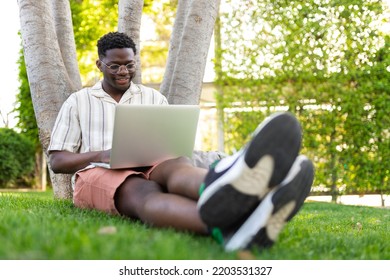 Young Black Man Using Laptop In Public Park. African American Male College Student Doing Homework On Campus.Copy Space.