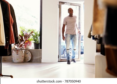 Young Black Man Walking Into A Clothes Shop And Closing Door