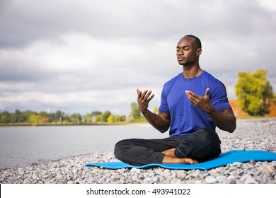 Young Black Man Wearing Athletic Wear Sitting On The Beach Exercising Yoga